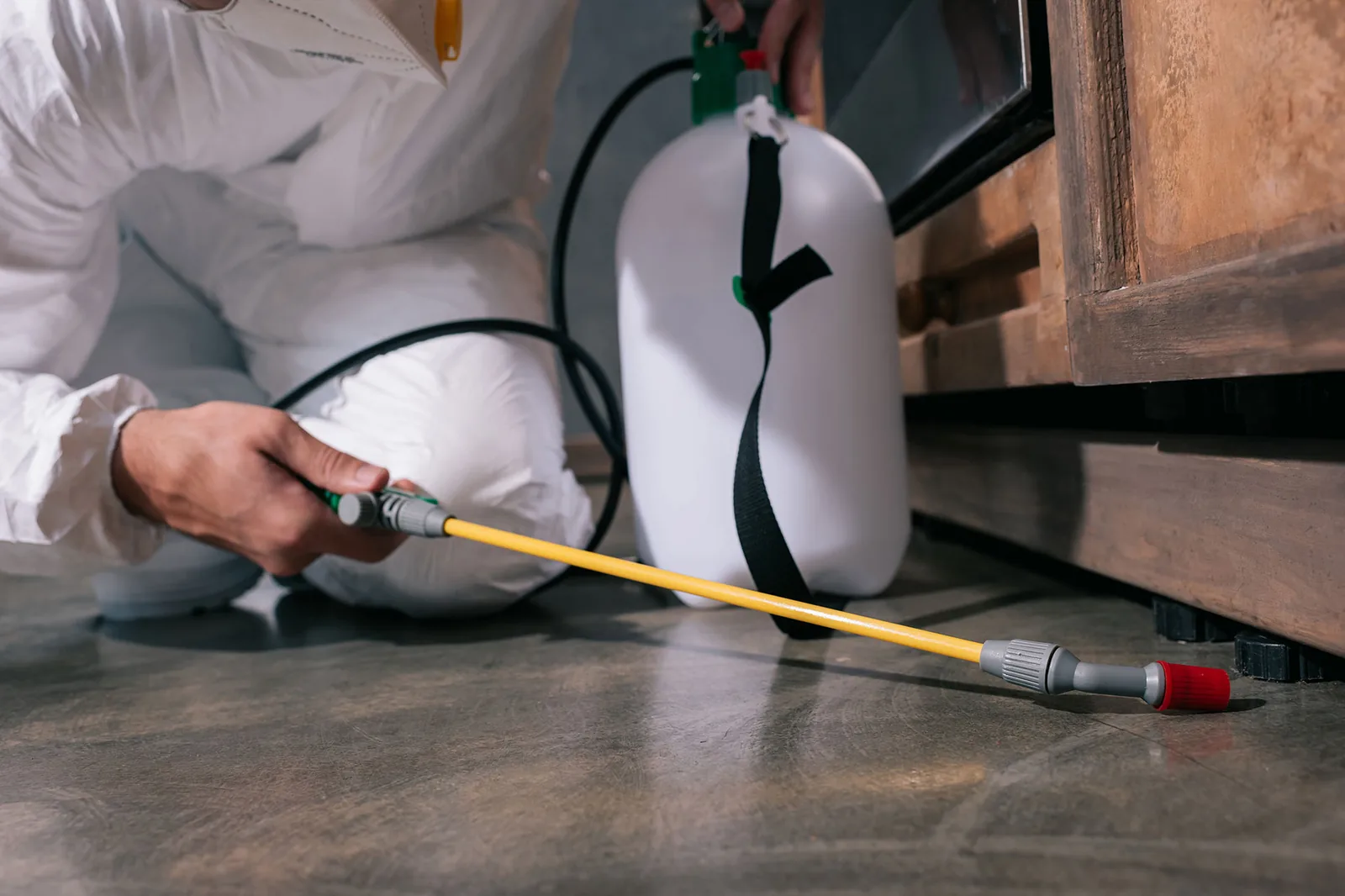 Ridtechs technician spraying a residual pest treatment along the floor of a Las Vegas home